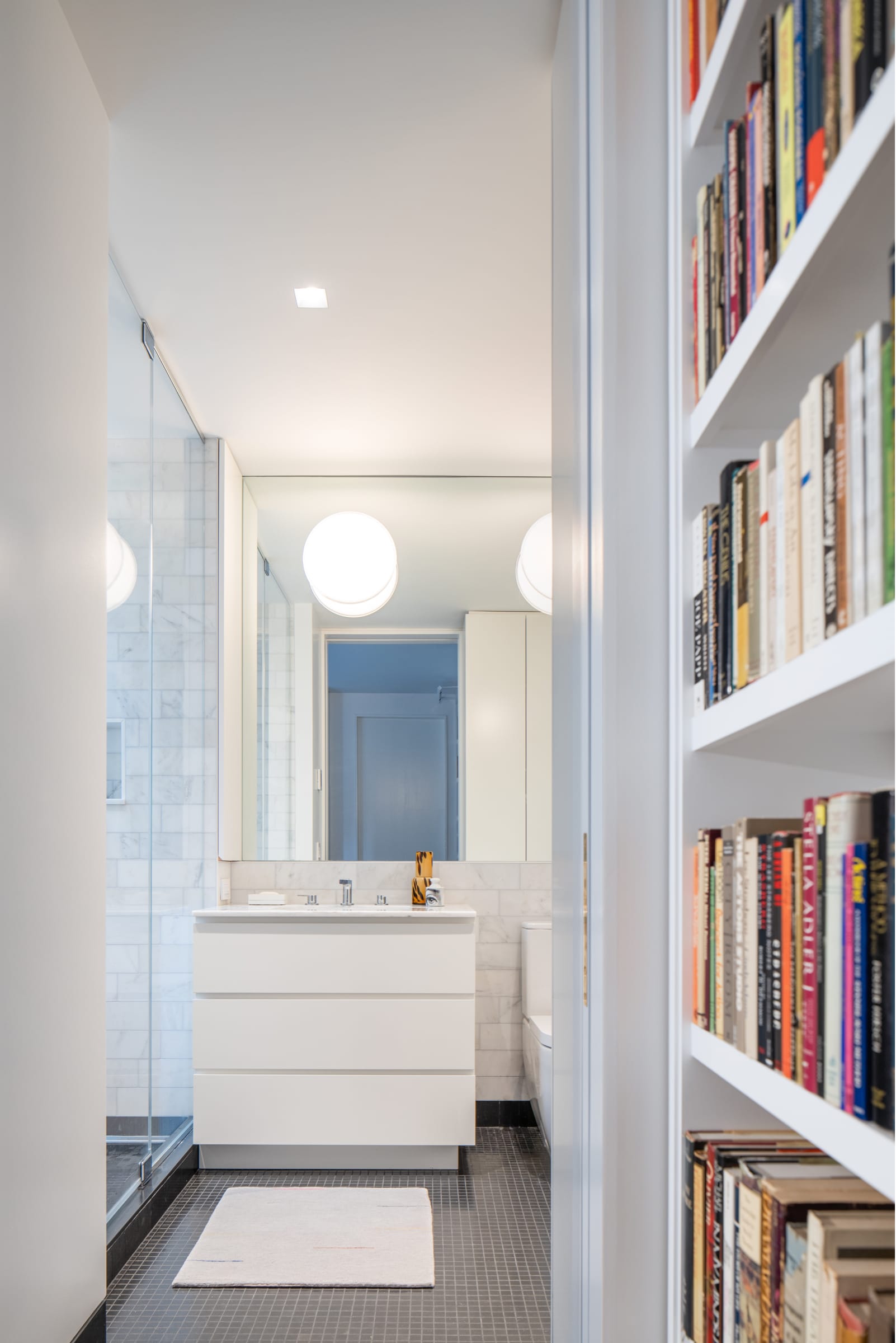 Bathroom with custom shower enclosure, white vanity cabinet and black floor tiles